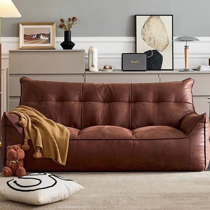 Brown leather sofa in a living room with decorative items and a lamp.