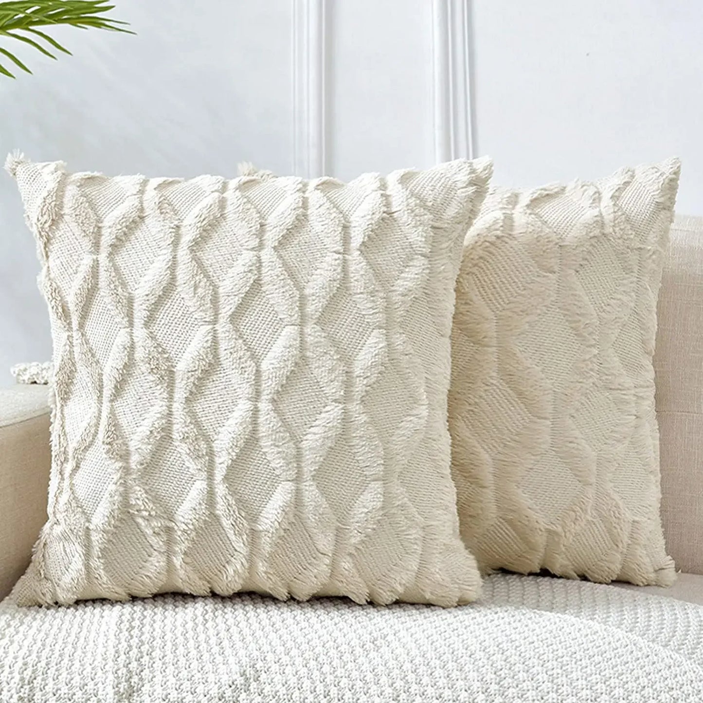 Two textured cream pillows on a sofa against a light background