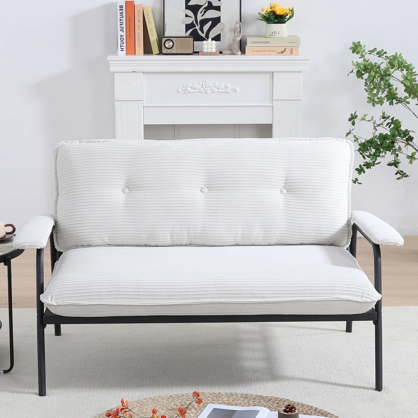 White futon sofa in a room with a white wall and a small table.