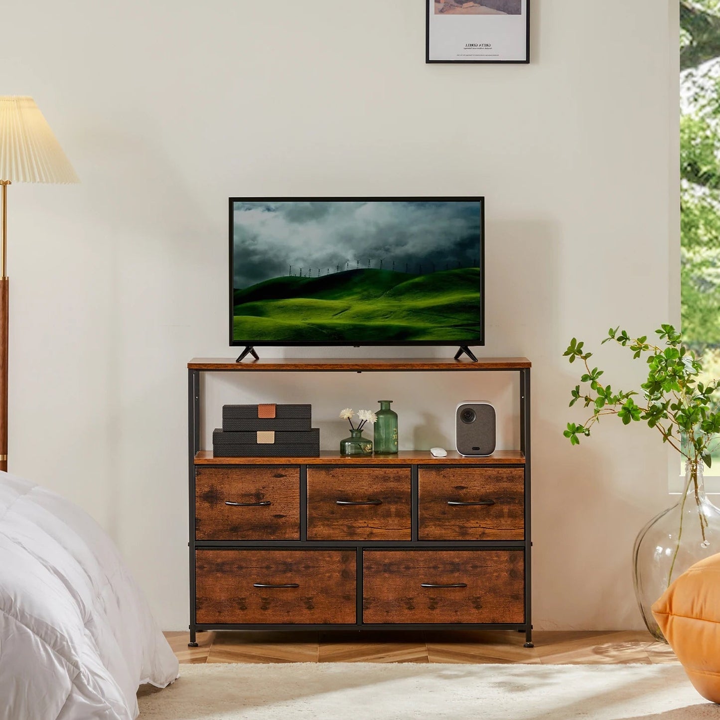 A brown JHK fireplace TV stand dresser with five fabric drawers, placed in a bedroom setting with a flat-screen TV on top.