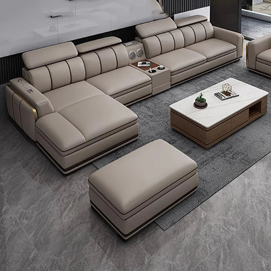 Beige sectional sofa with ottoman and coffee table in a modern living room setting.