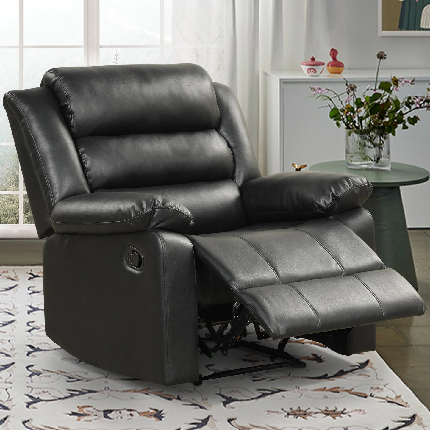 Black leather recliner chair in a living room setting with a table and decor items.