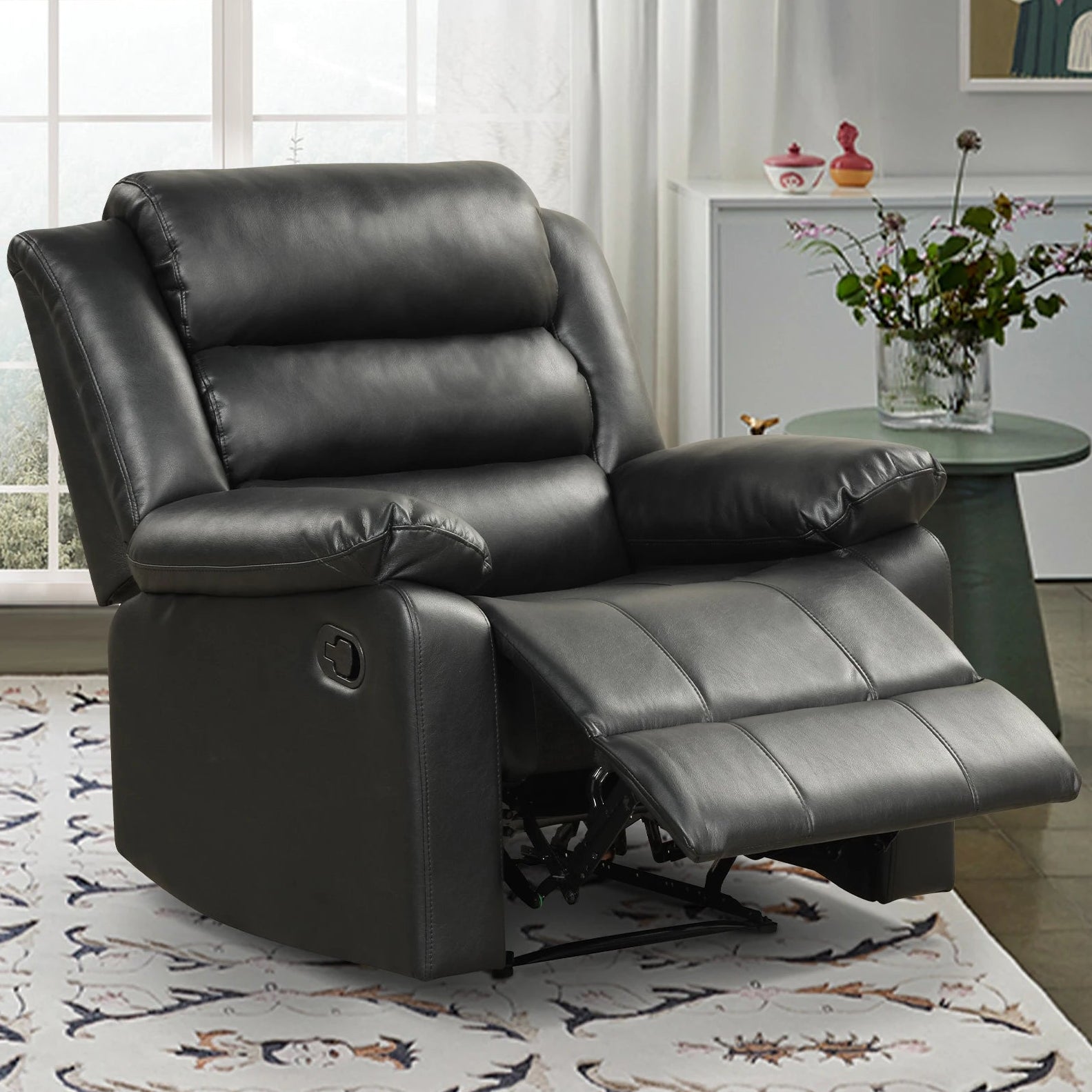Black leather recliner chair in a living room setting with a table and decor items.