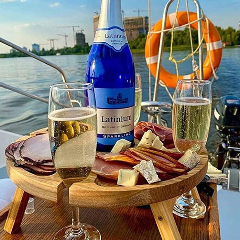 Bottle of Latium sparkling wine with two glasses on a charcuterie board by a waterfront.