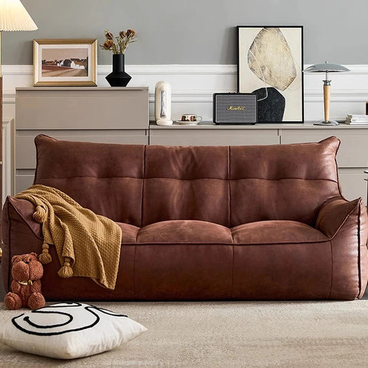 Brown leather sofa in a living room with decorative items and a lamp.