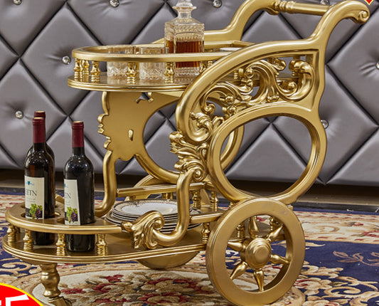 Gold bar cart with wine bottles on a patterned rug against a gray textured wall.