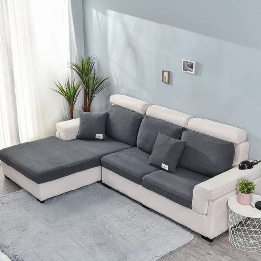 Gray and white sectional sofa in a living room setting with plants and a small table.