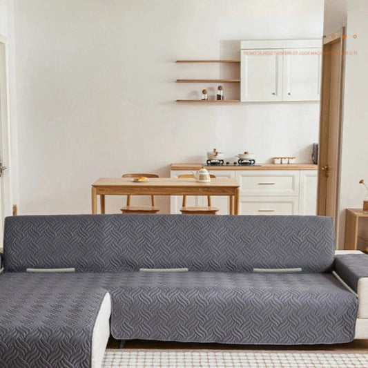 Gray patterned sofa cover on a sofa in a living room with a kitchen in the background.