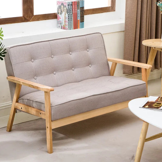 Gray sofa with wooden frame in a room setting with books and a mirror.
