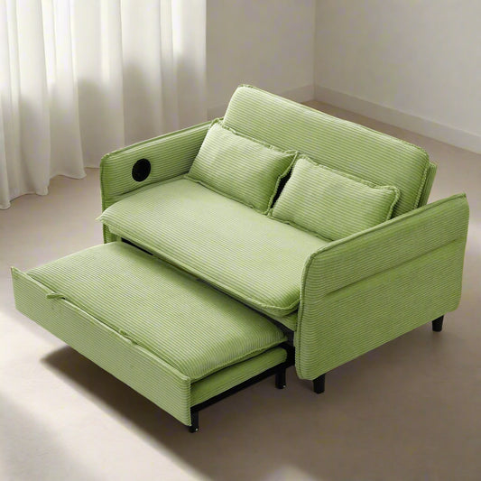 Green sofa bed in a room with a plant and fireplace.