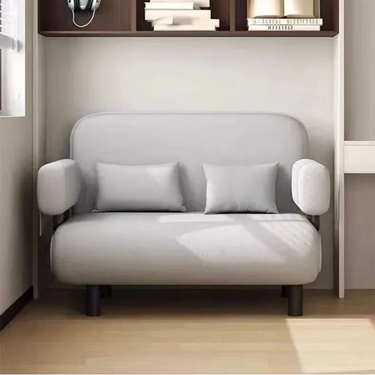 Modern gray sofa in a minimalistic room with a bookshelf and desk.
