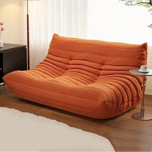 Orange sofa in a living room setting with a small table and decorative elements.