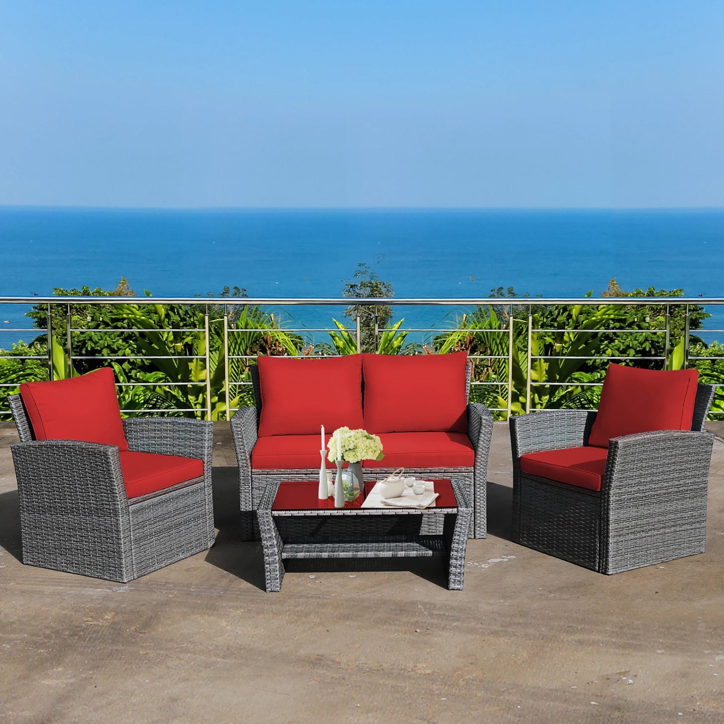 Outdoor furniture set with red cushions and a small table on a balcony with ocean view.