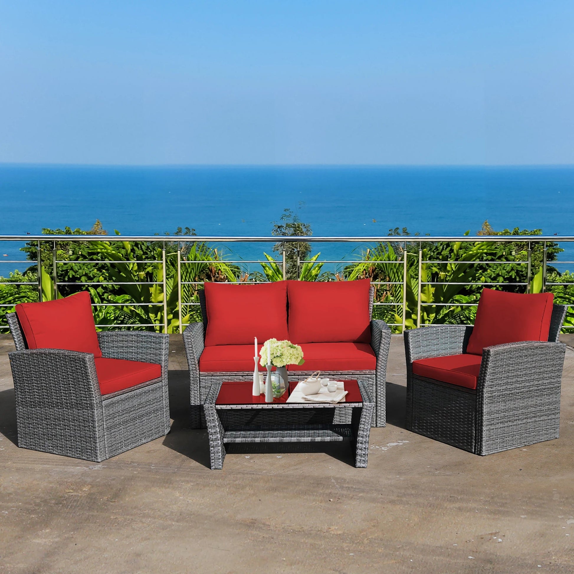 Outdoor furniture set with red cushions and a small table on a balcony with ocean view.