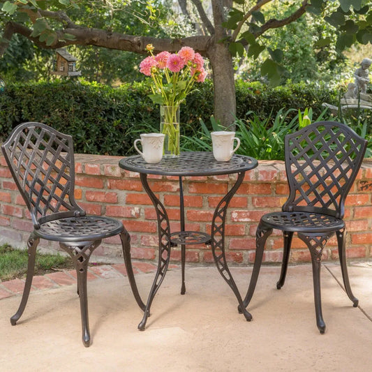 Outdoor patio set with two chairs and a small table, featuring a vase of pink flowers on a brick wall background.