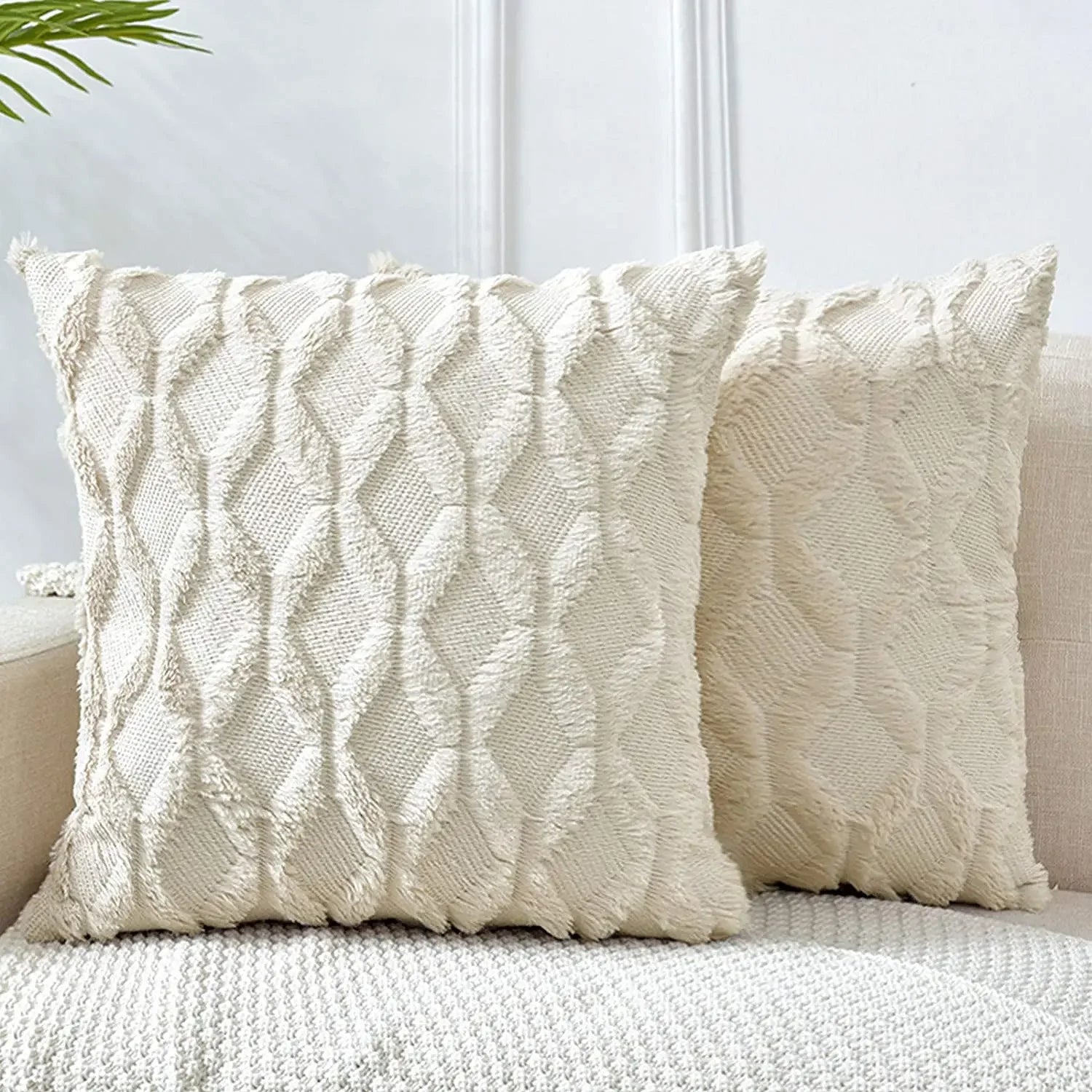 Two textured cream pillows on a sofa against a light background
