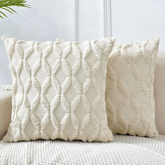 Two textured cream pillows on a sofa against a light background