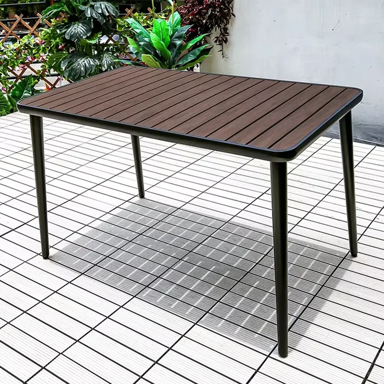 Wooden outdoor table on a tiled patio with plants in the background